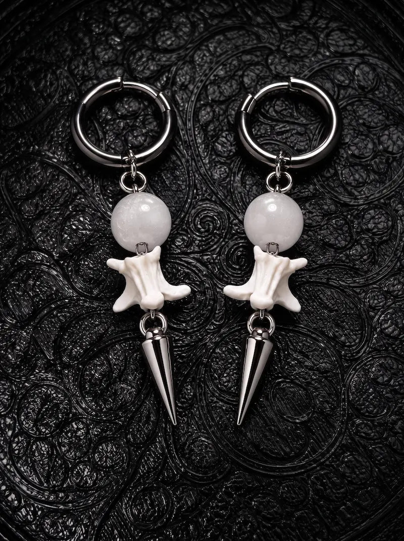 Prismatic Fang snake bone earrings with milky white beads and polished silver-tone spikes on black patterned fabric