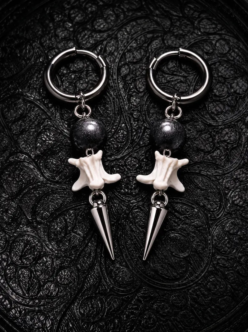 Prismatic Fang snake bone earrings with black beads and polished silver-tone spikes on black patterned fabric