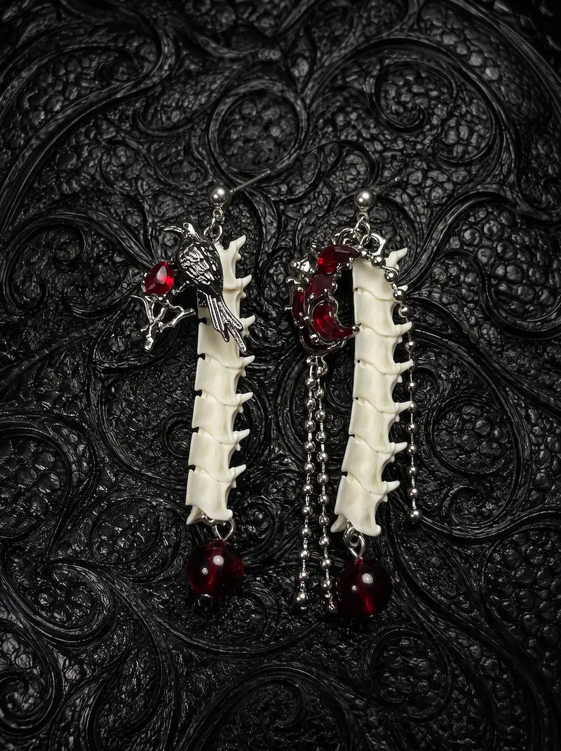 Ravenmoon Snake Bone Earrings, pair of pale vertebrae drop earrings with dark red beads and metal chains on black fabric