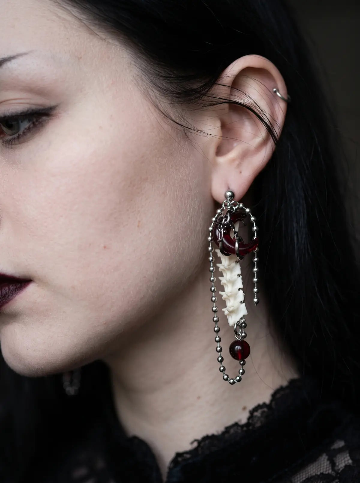Ravenmoon Snake Bone Earrings, close view of Ravenmoon earring showing its pale spine motif and chain tassels