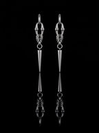 Pair of silver Razor Fang Spike Earrings with long tapered spike pendants on a black background