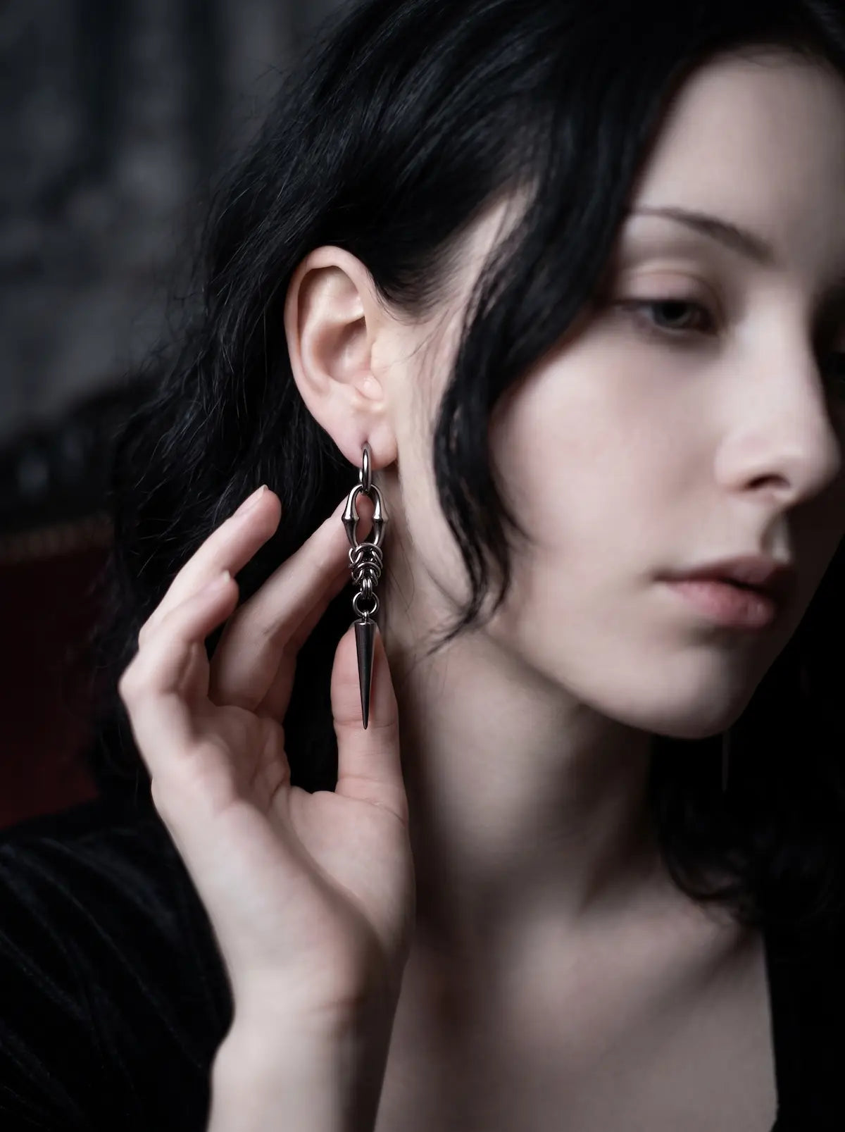 Gothic woman wearing Razor Fang Spike Earrings with hand raised beside the earring
