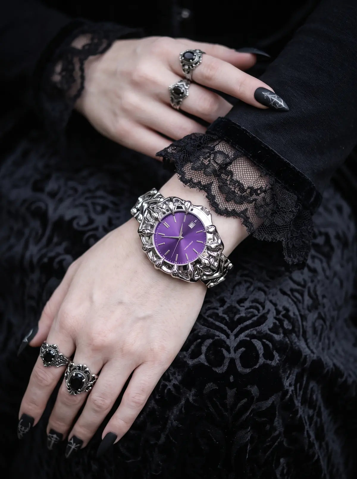 Razorclaw Gothic Watch, purple watch face and sculpted case shown on a wrist above black lace gloves