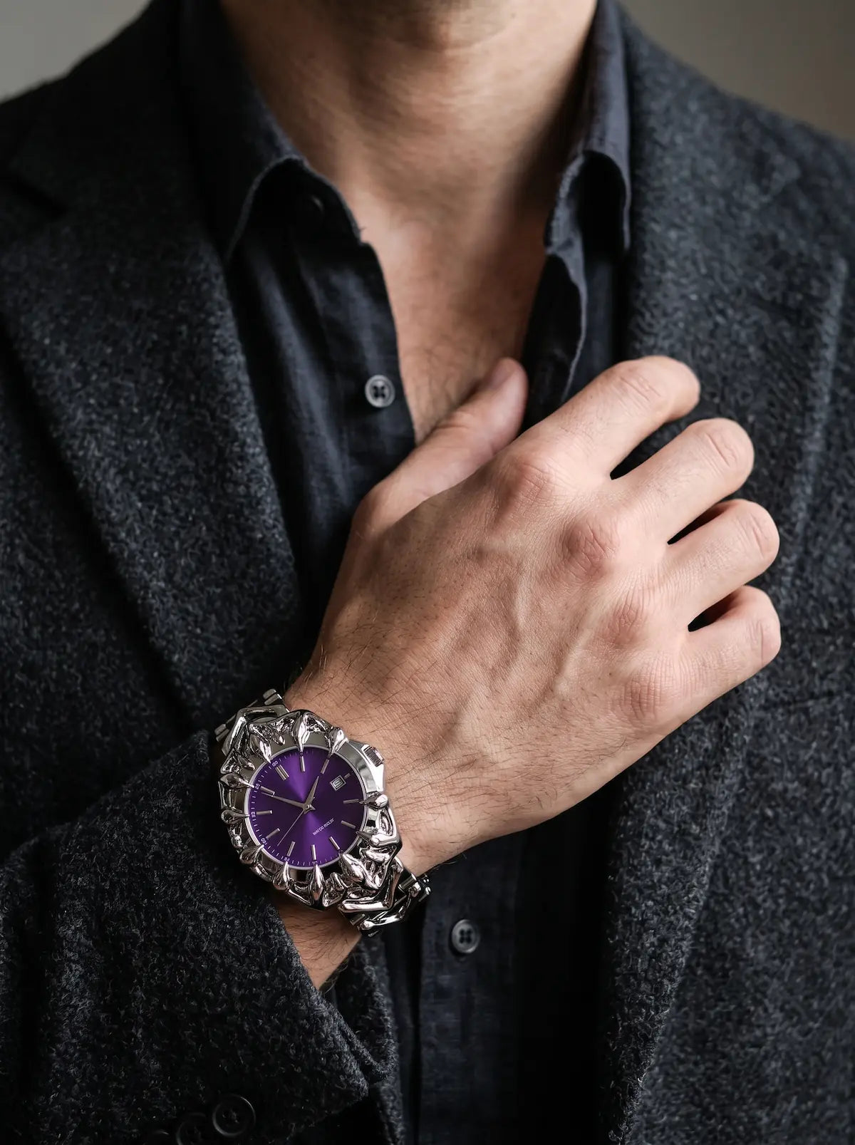 Razorclaw Gothic Watch, purple-dial watch worn on a raised wrist against a charcoal shirt