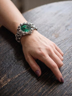 Razorclaw Gothic Watch, green-dial watch worn on a wrist resting on a weathered wooden tabletop