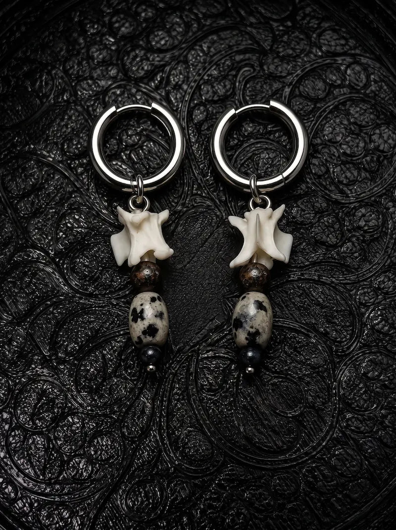 Relicstone snake bone earrings with brown beads, speckled oval stones and black bead tips on black patterned fabric