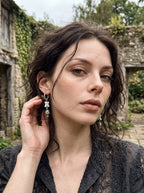 Relicstone snake bone earring with speckled stone beads, worn beside a hand touching the ear