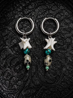 Relicstone snake bone earrings with turquoise-colored beads and oval speckled stones on black patterned fabric