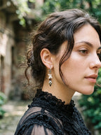Side view of a dark Relicstone snake bone earring worn above a black lace collar