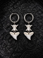 Riptide bull shark tooth and snake bone earrings with broad triangular teeth, displayed on black patterned fabric