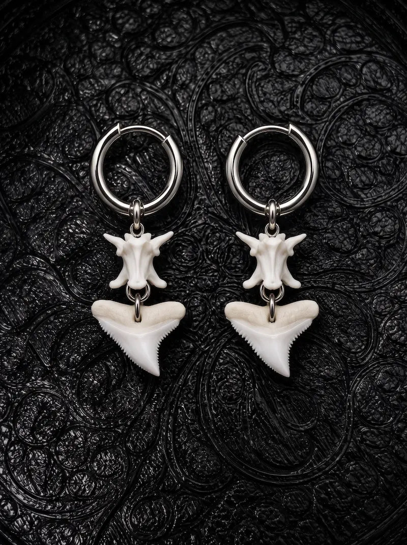 Riptide bull shark tooth and snake bone earrings with broad triangular teeth, displayed on black patterned fabric