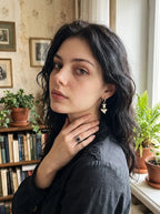 Riptide shark tooth and snake bone earring worn with a dark shirt and a hand at the neck