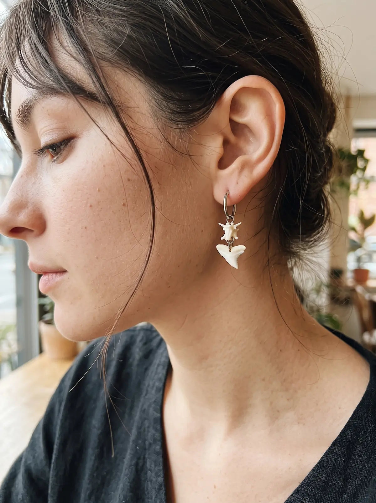Close-up side view of a Riptide earring showing a white snake vertebra above a triangular shark tooth