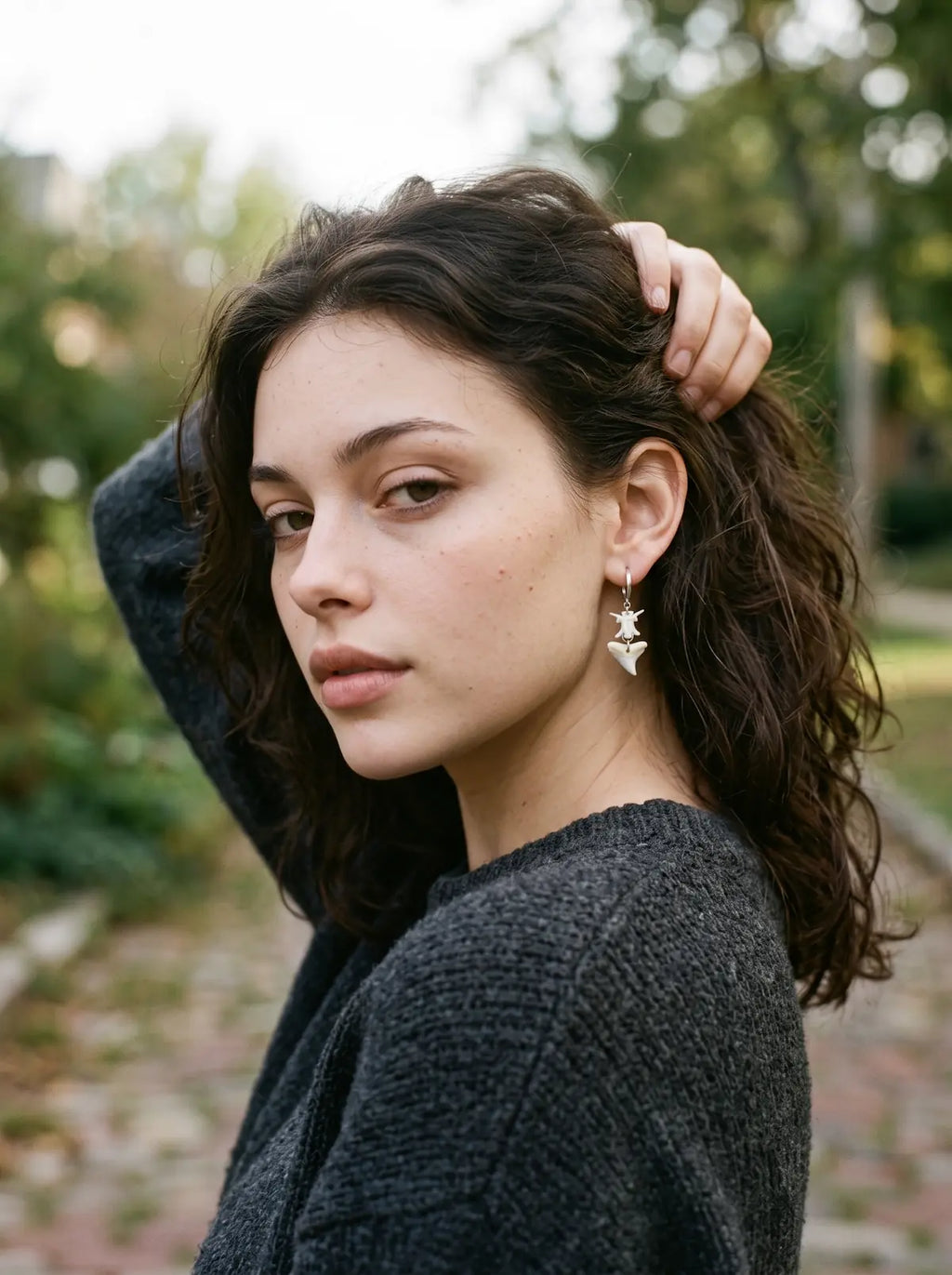Riptide shark tooth and snake bone earring worn outdoors with the hair lifted away from the ear