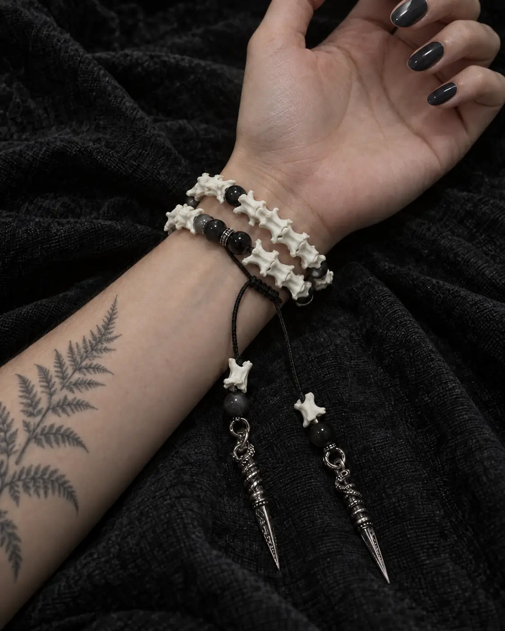 Palm-up view of the Ritual Spear snake bone bracelet showing two rows and its long dangling metal drops