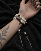 Palm-up view of the Ritual Spear snake bone bracelet showing two rows and its long dangling metal drops