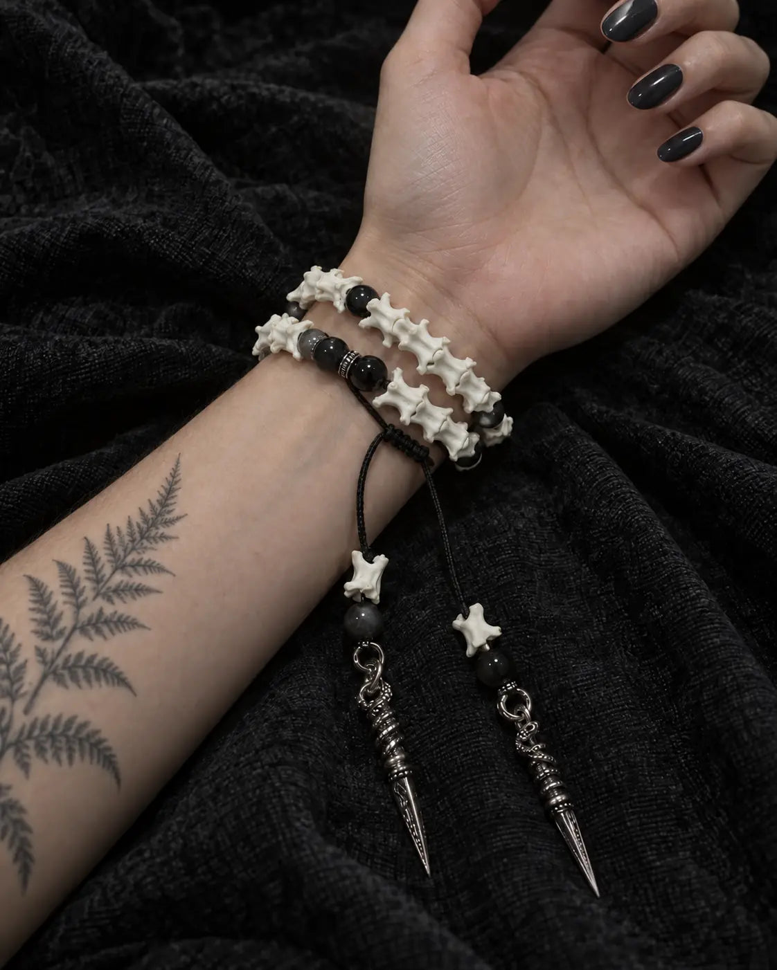 Palm-up view of the Ritual Spear snake bone bracelet showing two rows and its long dangling metal drops