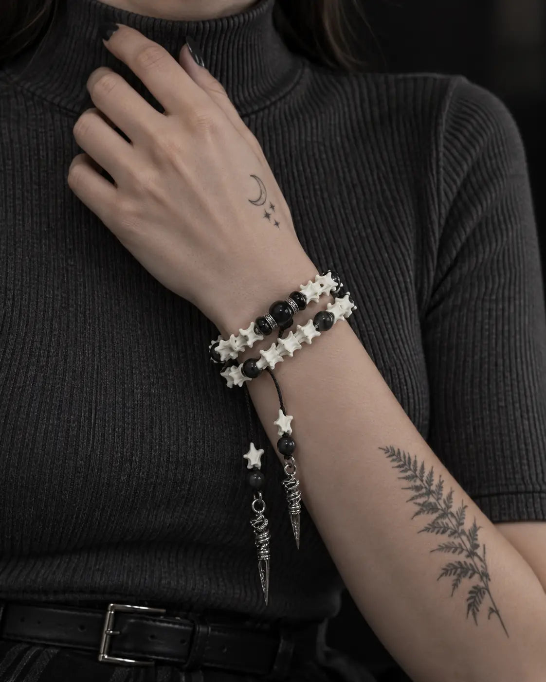 Ritual Spear snake bone bracelet worn with the hand at a dark ribbed collar and both spear drops hanging down