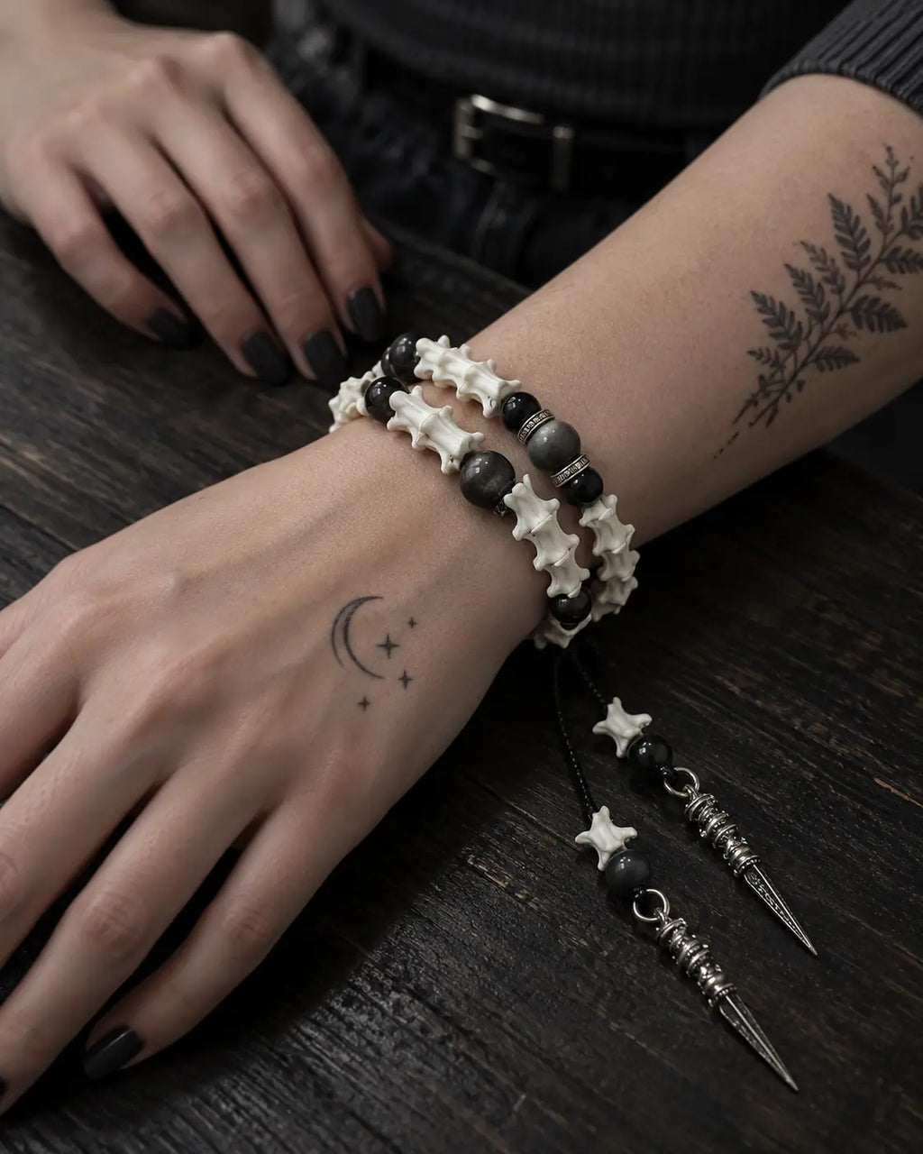 Top view of the Ritual Spear snake bone bracelet on a wrist resting on a wooden table