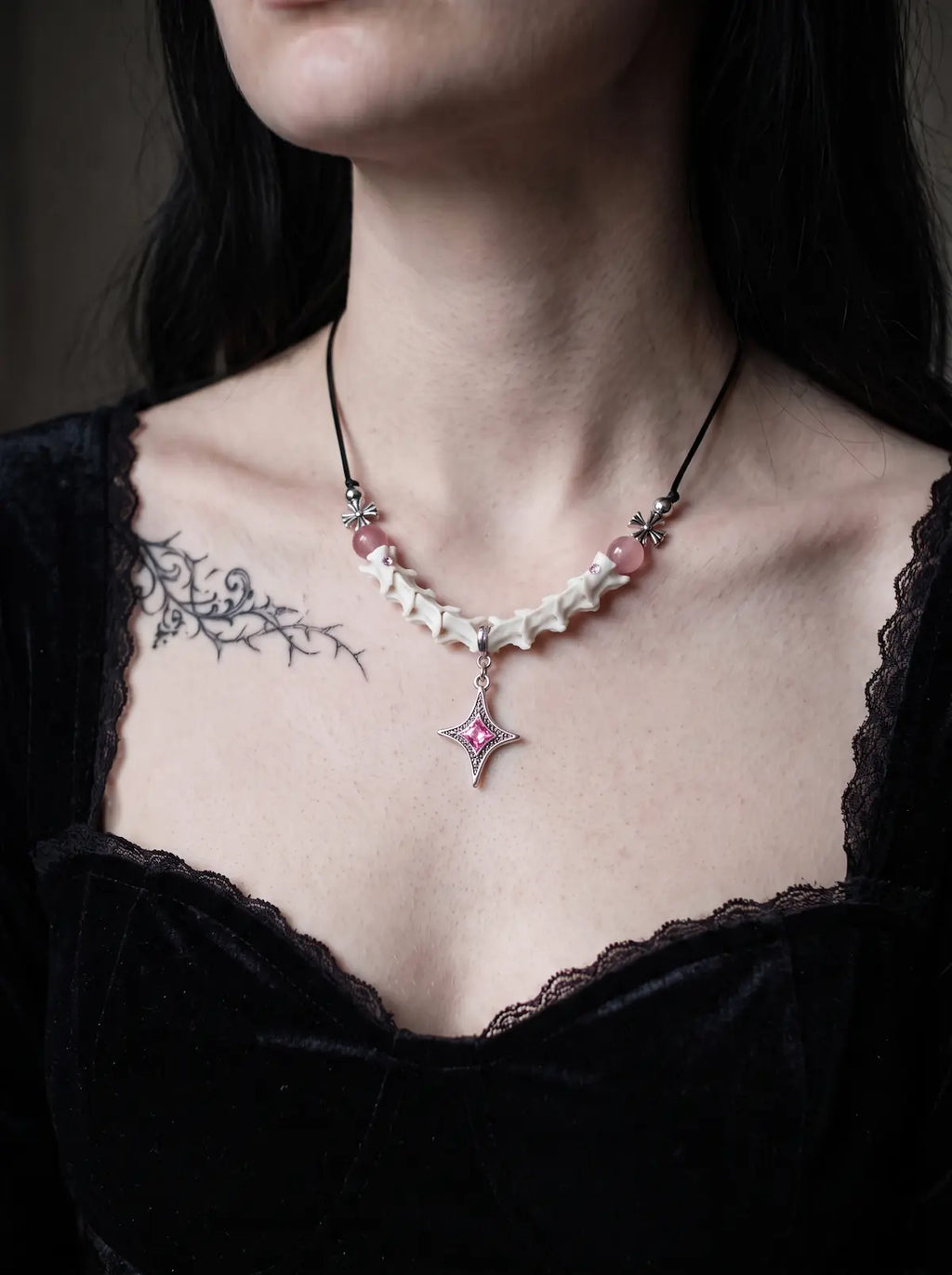 Roselight Snake Bone Necklace, pale vertebrae necklace with pink beads worn above a black velvet neckline