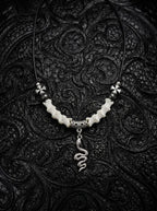 Sablecoil Snake Bone Necklace, white vertebrae necklace with black bead accents and a coiled metal snake pendant