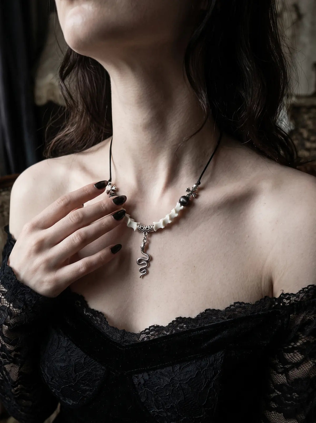 Sablecoil Snake Bone Necklace, silver-tone coiled serpent pendant hanging below a pale snake bone necklace