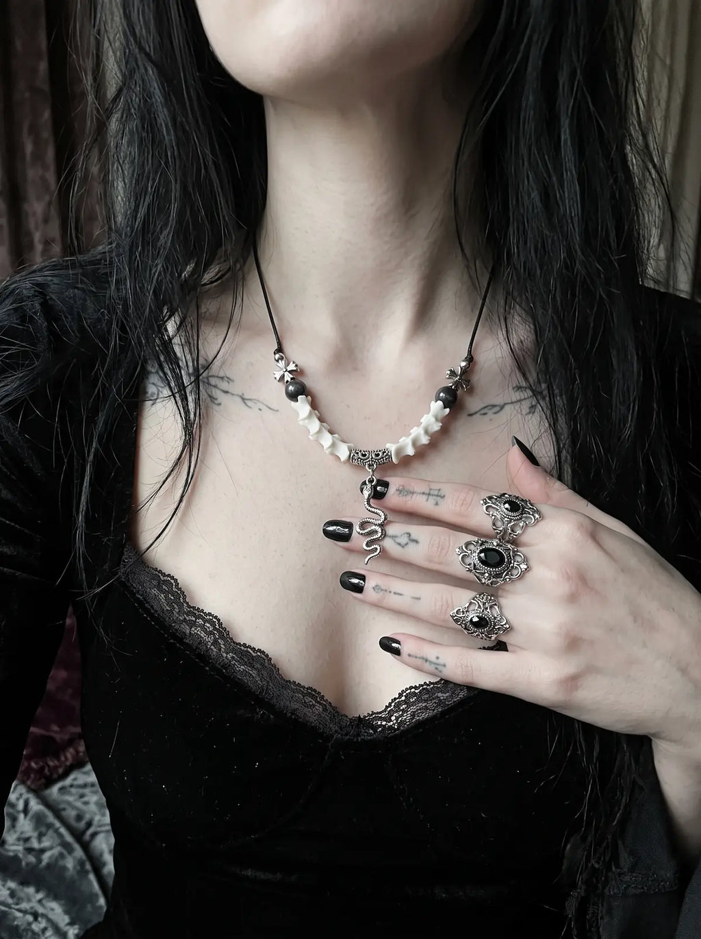 Sablecoil Snake Bone Necklace, front neck detail of white vertebrae and dark bead necklace with snake charm