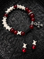 Scarlet Cross snake bone bracelet with red beads, engraved silver-tone spacers and a hanging cross on black fabric