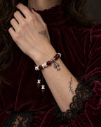 Scarlet Cross snake bone bracelet worn with the hand near a burgundy velvet collar