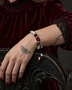 Scarlet Cross snake bone bracelet on a wrist resting over the carved arm of a dark chair