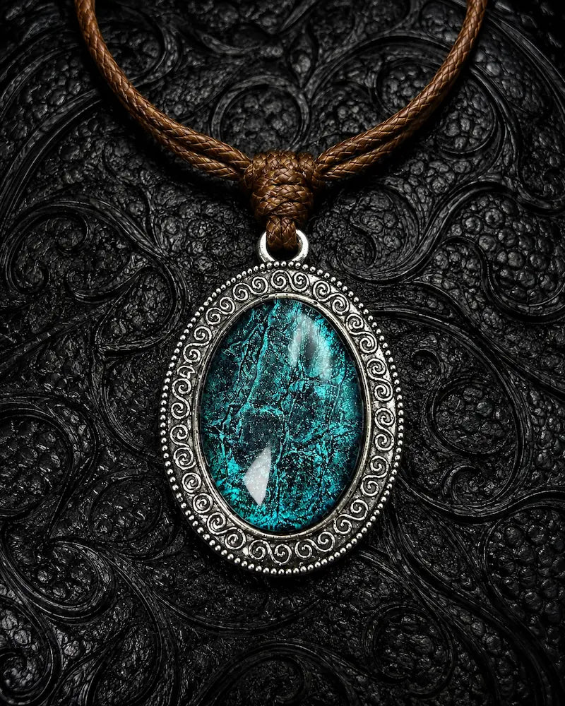 Serpent Relic snakeskin pendant necklace in Teal, showing blue-green scales within an ornate oval frame
