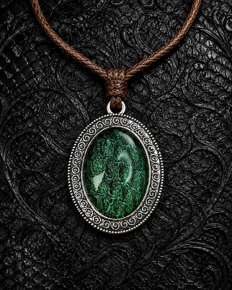 Serpent Relic snakeskin pendant necklace in Emerald Green, displayed on black textured fabric