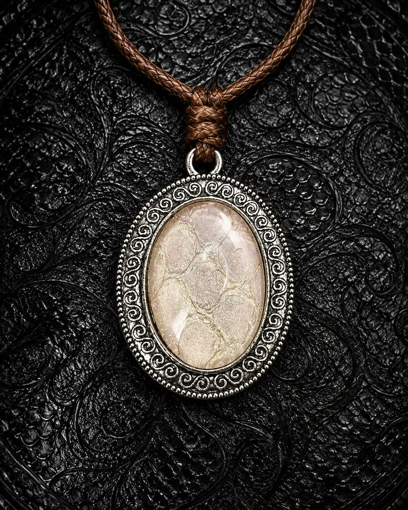 Serpent Relic snakeskin pendant necklace in Ivory, showing pale scales and an ornate silver-tone frame