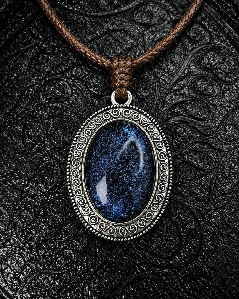 Serpent Relic snakeskin pendant necklace in Midnight Blue, with a brown braided cord on a black background