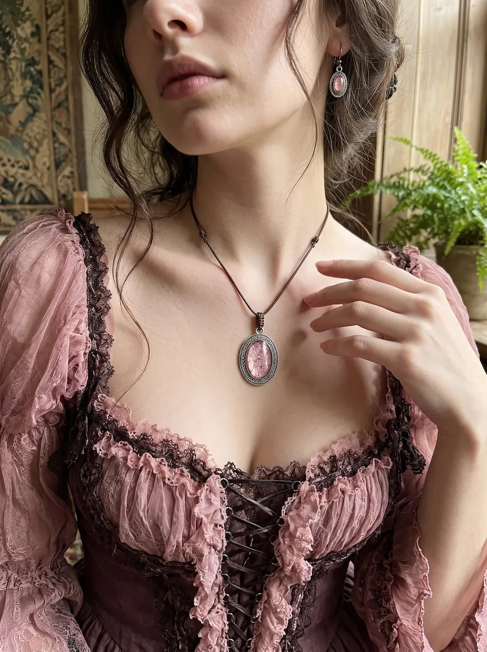 Dusty Rose Serpent Relic snakeskin pendant worn above a pink lace-trimmed corset top