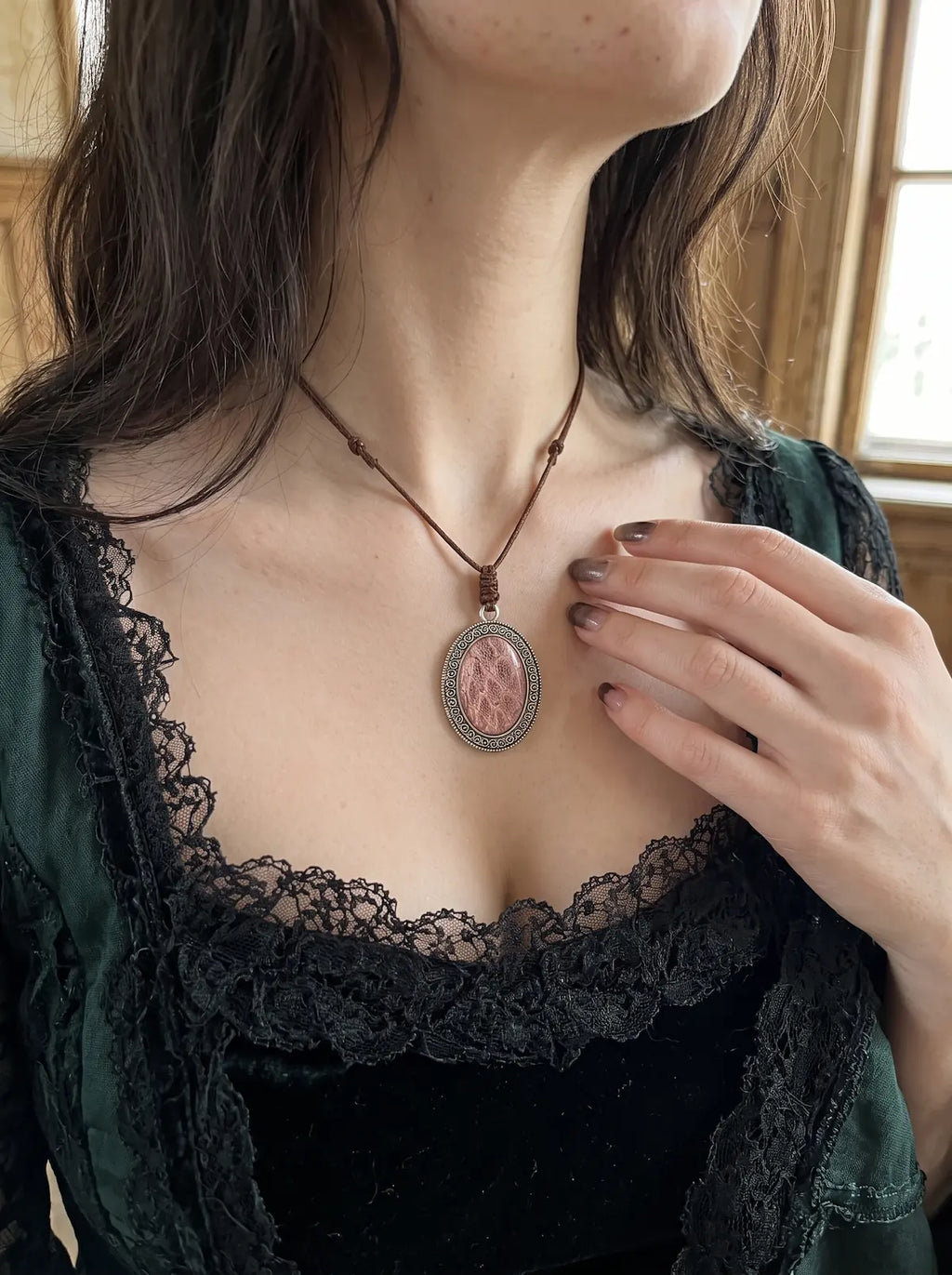 Close-up of the Dusty Rose Serpent Relic snakeskin pendant worn above a dark lace neckline