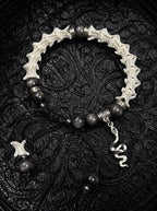 Shadow Serpent snake bone bracelet with dark gray beads, engraved spacers and a dangling silver-tone snake charm