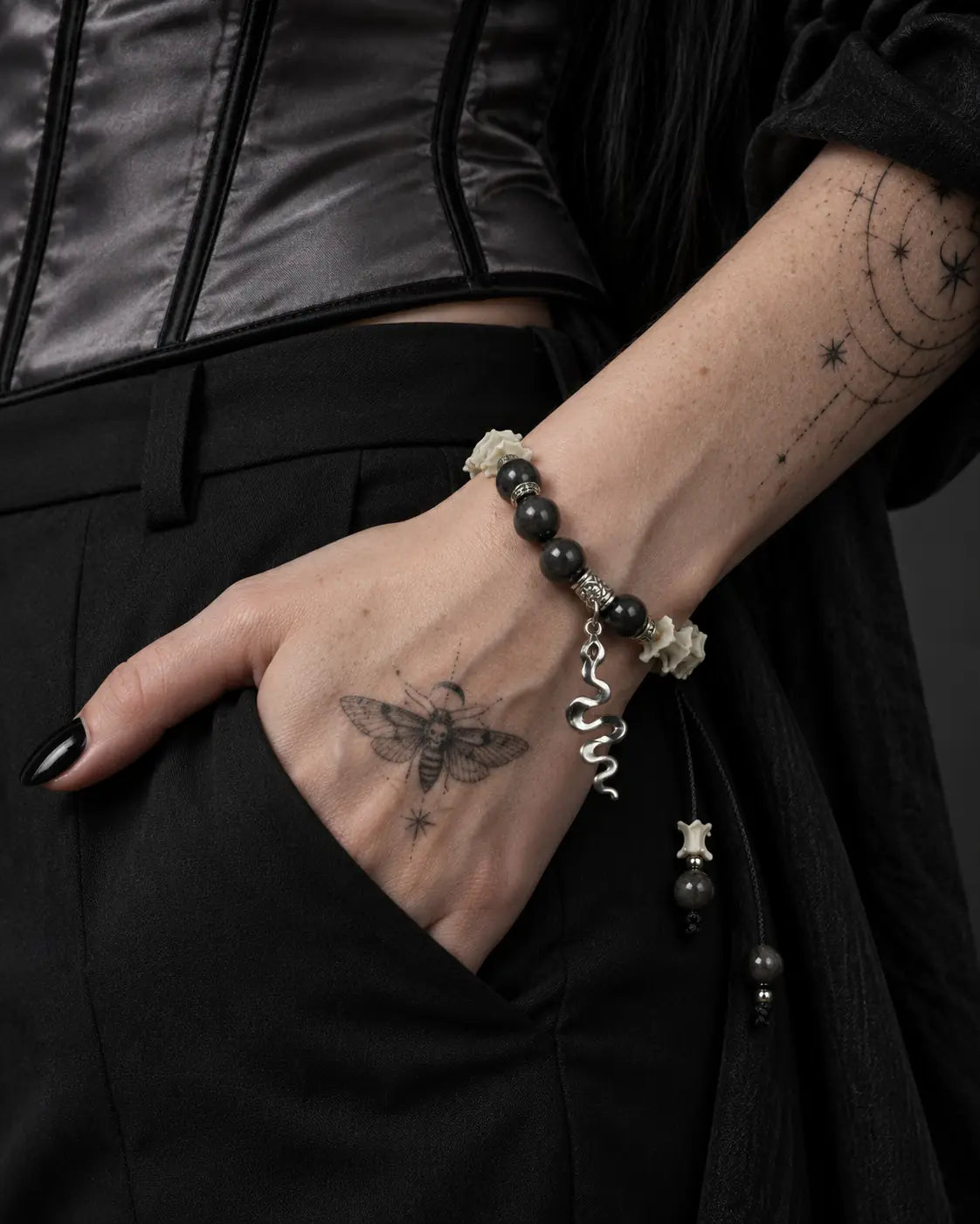 Shadow Serpent snake bone bracelet worn with the hand tucked into a black skirt pocket