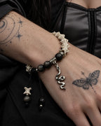 Close-up of the Shadow Serpent snake bone bracelet showing dark gray beads, engraved spacers and a silver-tone snake drop