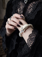 Silver Omen Snake Bone Bracelet, close view of pale preserved snake head bracelet worn near a black lace collar