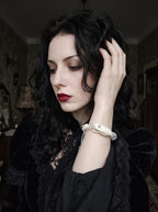 Silver Omen Snake Bone Bracelet, pale snake bone bracelet worn on a raised wrist by a model with dark hair