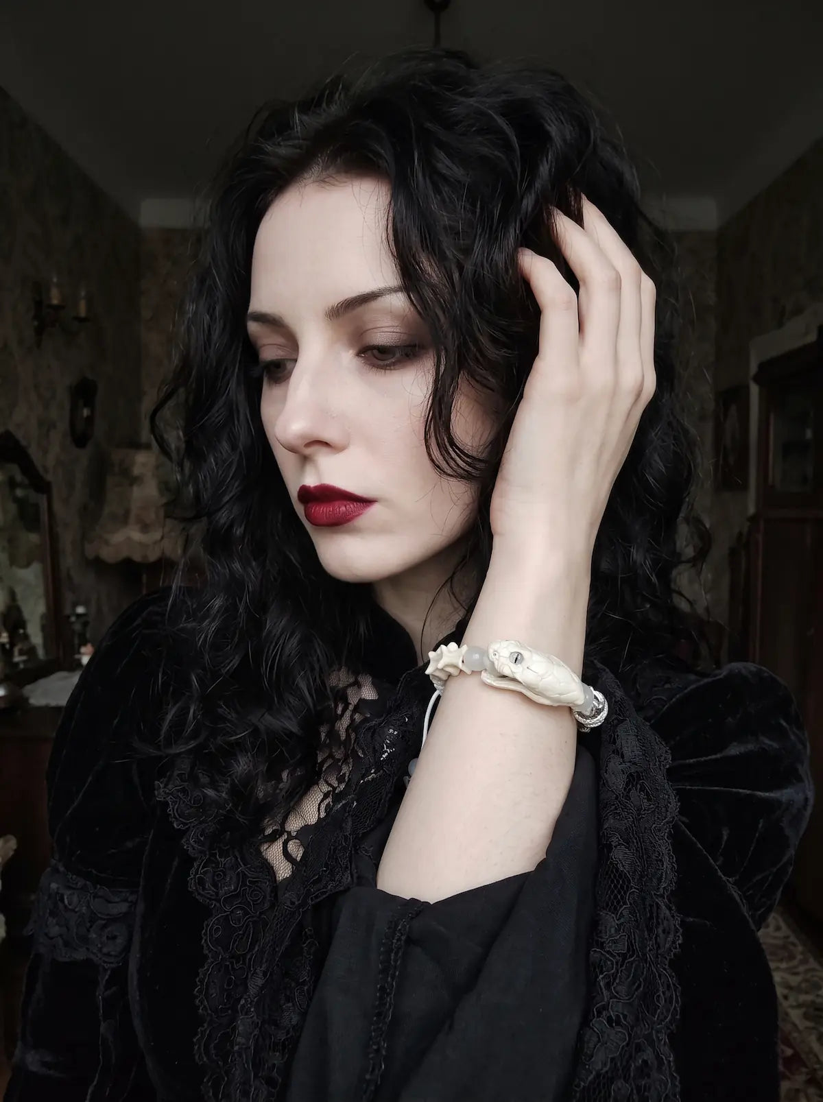 Silver Omen Snake Bone Bracelet, pale snake bone bracelet worn on a raised wrist by a model with dark hair
