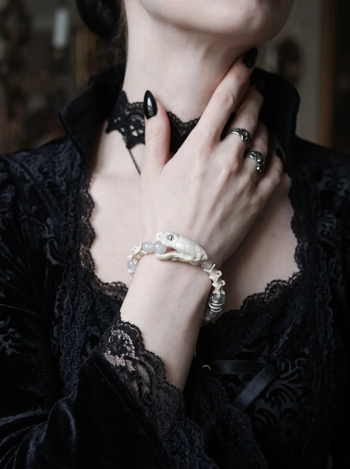 Silver Omen Snake Bone Bracelet, pale snake head bracelet worn at the wrist while fingers touch the neck