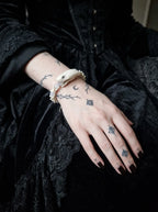 Silver Omen Snake Bone Bracelet, white snake bone bracelet with dangling silver-tone charms over black sleeves