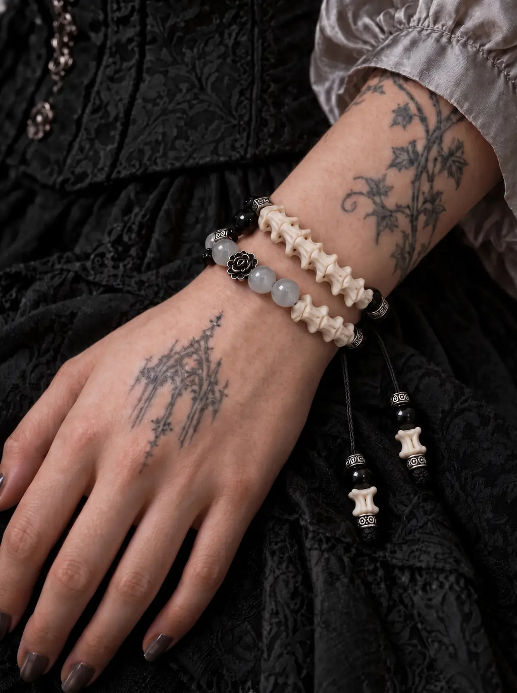 Smoky Rosette snake bone bracelet wrapped twice around a tattooed wrist against black lace