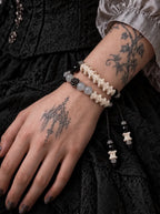 Smoky Rosette snake bone bracelet wrapped twice around a tattooed wrist against black lace