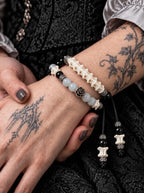 Close-up of the Smoky Rosette snake bone bracelet showing gray beads, a floral centerpiece and hanging cord ends