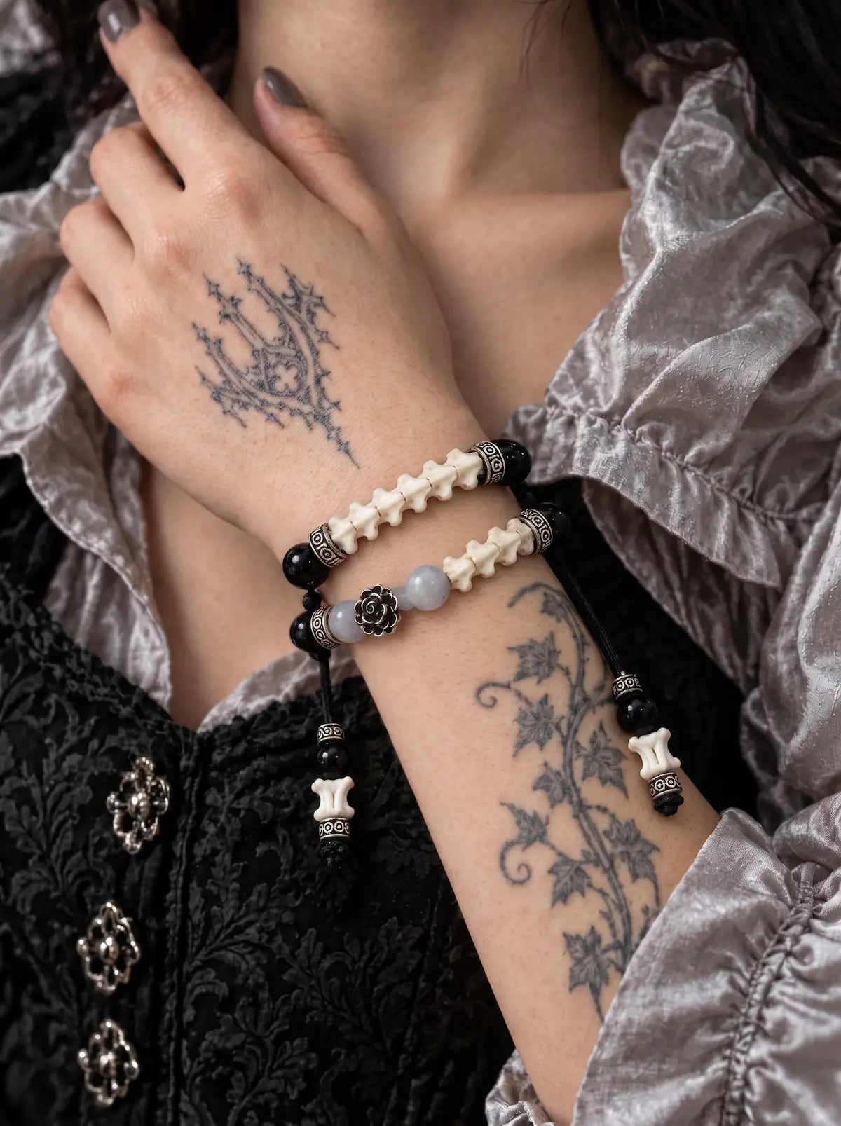 Smoky Rosette snake bone bracelet worn with the hand at the neck, showing two rows and dangling bone-tipped cords