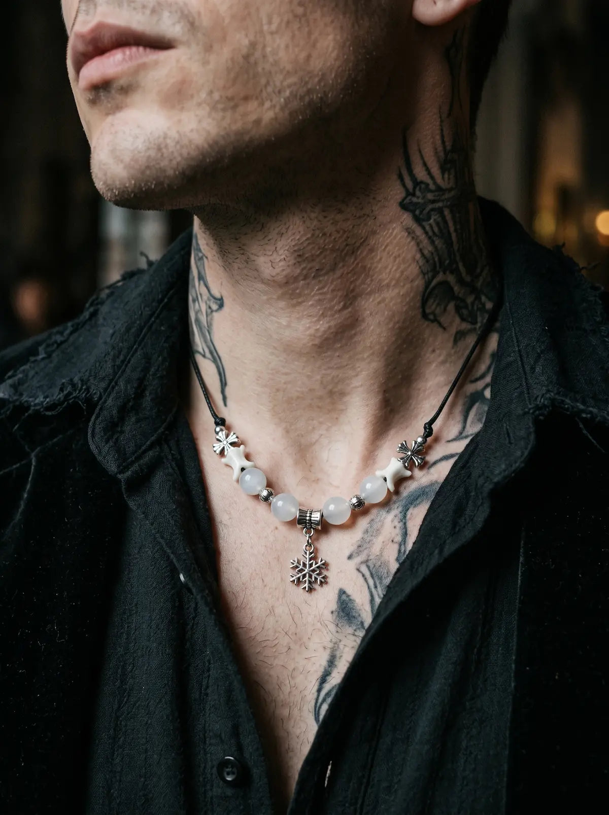 Snowbound Snake Bone Necklace, snowflake pendant and pale bone necklace against a tattooed neck and black shirt