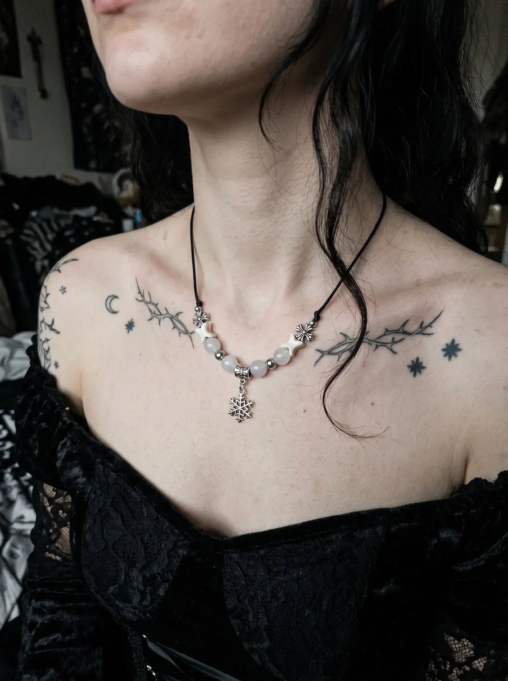 Snowbound Snake Bone Necklace, white bone necklace with silver-tone snowflake charm above a black lace top
